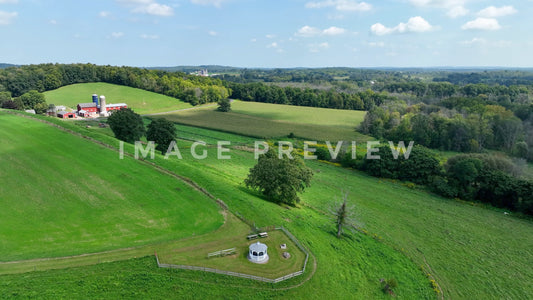 stock photo Landscape with green rolling hills with farmhouse and gazebo