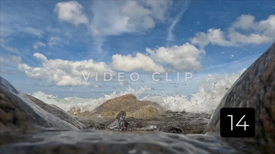 CLIP 14 - Slow motion - Rocky beach with waves and surf under blue sky with clounds