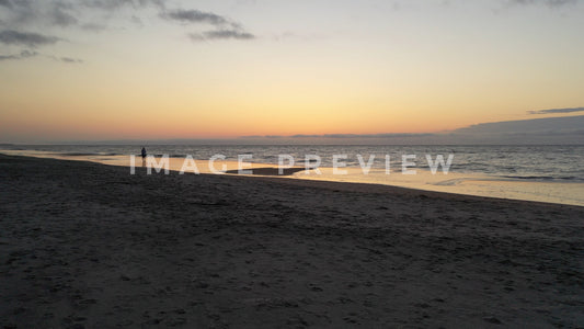 stock photo solo person walking on beach at sunrise