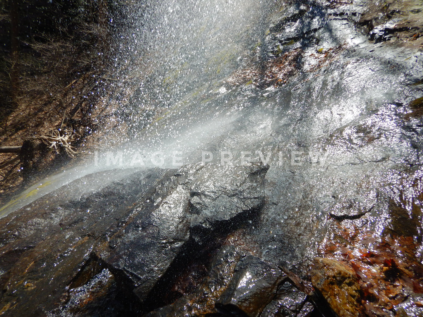 Photo - Misty spray from water falling on rock formation