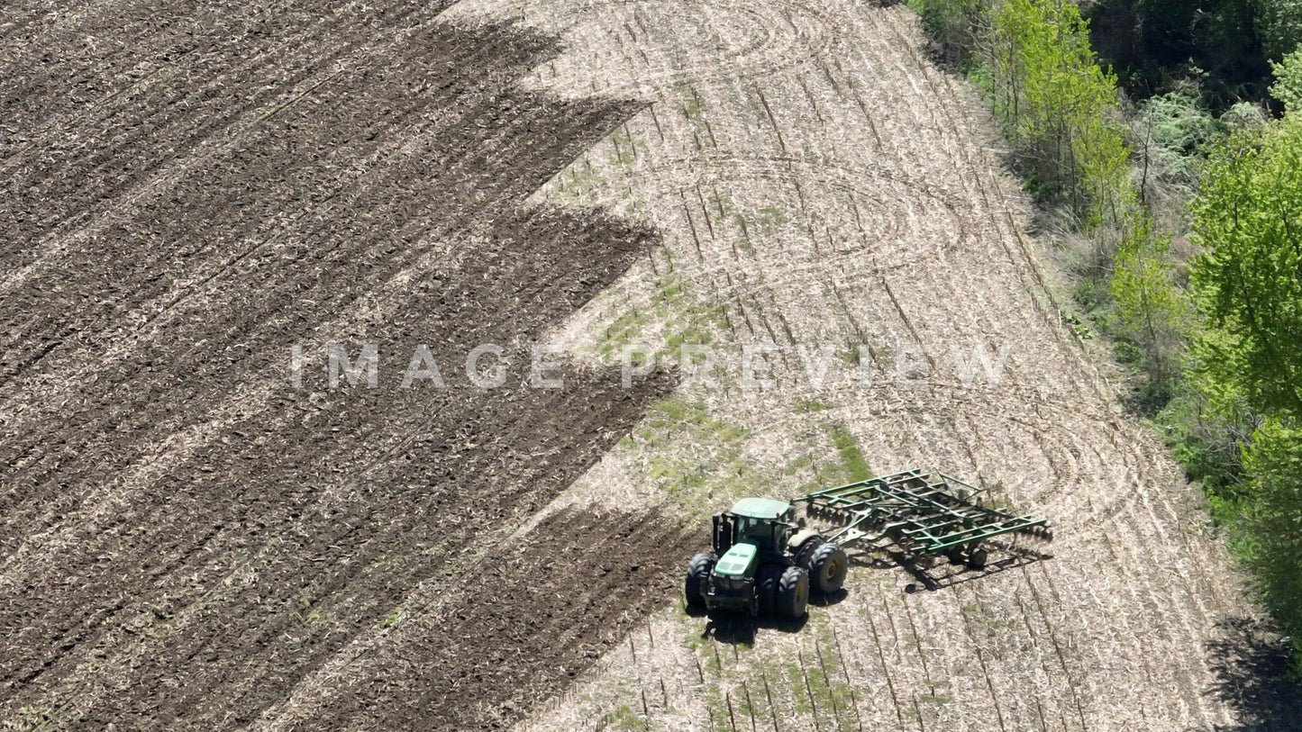 4k Still Frame - 7x zoom close up of farmer plowing cornfield in Springtime