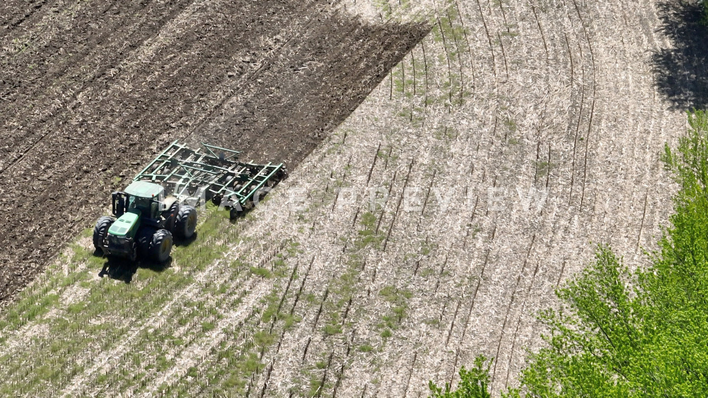 4k Still Frame - 7x zoom close up of farmer plowing cornfield in Spring