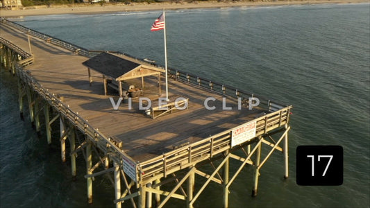 CLIP 17 - Pawleys Island, SC aerial dramatic spin around end of fishing pier with American flag waving