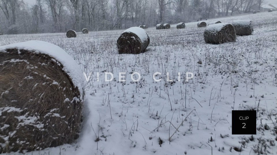 CLIP 2 - Flying low over hay bales covered in snow during Winter with person walking dogs in distance