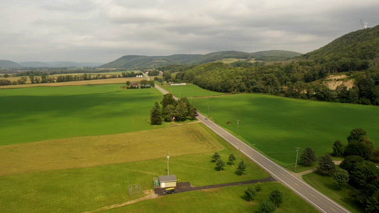 Video - Car traveling on country road past green fields and mountains in upper state New York
