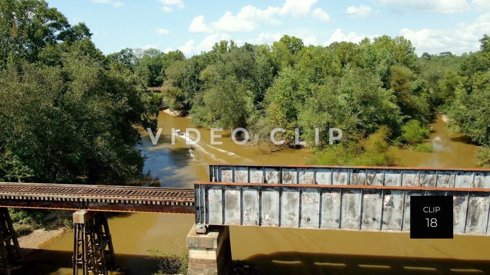 CLIP 18 - Montezuma, GA fisherman in boat motors past train bridge on Flint River