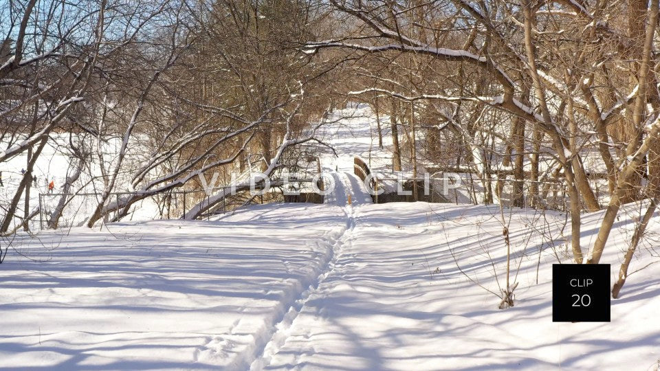 CLIP 20 - Snow covered walking trail with creek bridge in public park during Winter