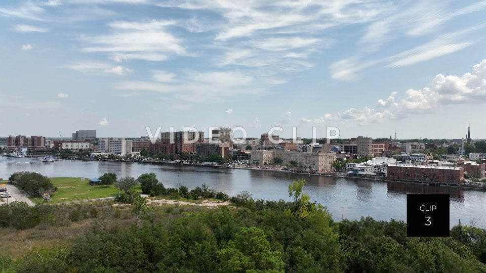 CLIP 3 - Wilmington, NC city skyline under blue sky and clouds beside Cape Fear River