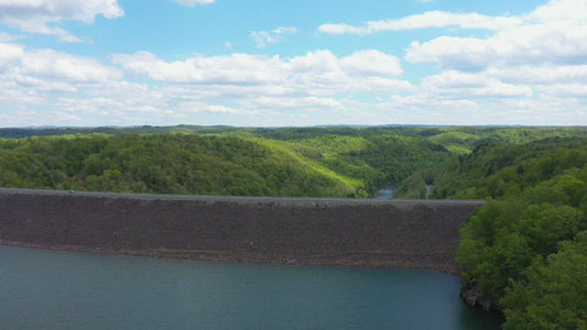 Video - Rising above earthen dam with car passing over at Lake Summersville in Virginia