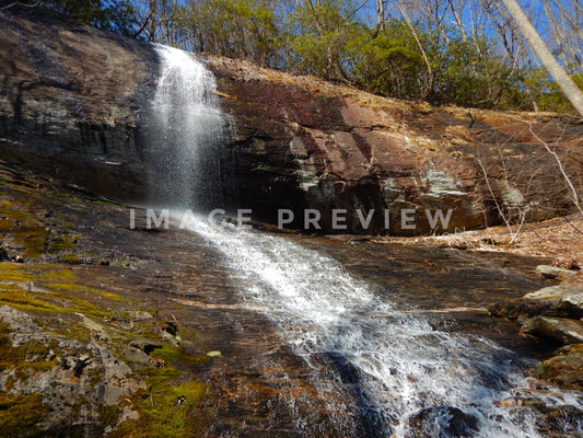 Photo - Waterfall spills over rocky cliff in forest