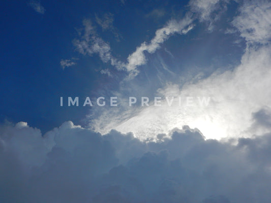 Photo - Sunlight peaks through clouds in blue sky