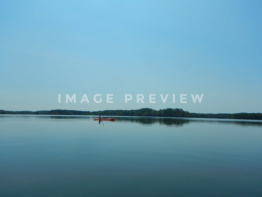 Photo - Solitary kayaker paddles on calm lake